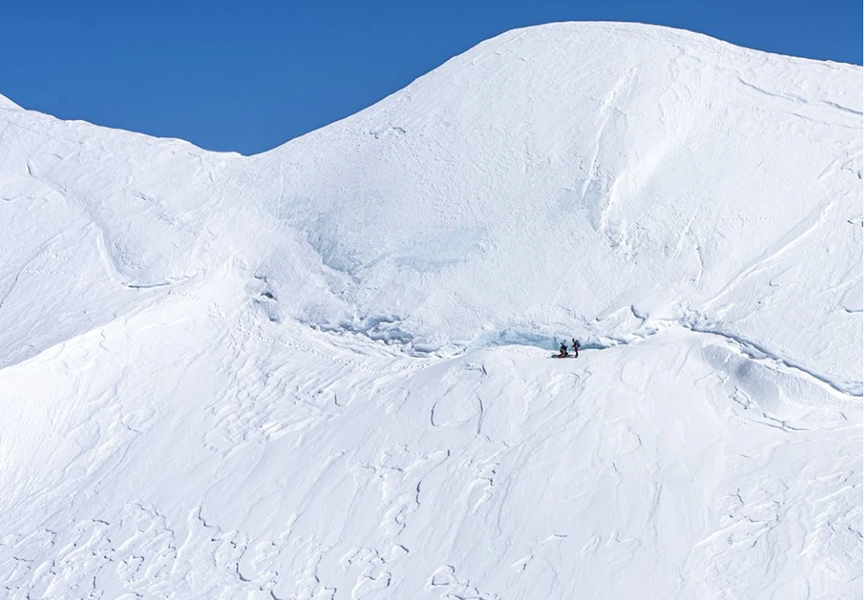 Two small figures on the snowy flank of Mt. Steele, on the way to Lucania