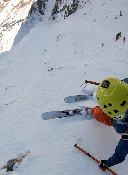 Skiers poised on edge of steep couloir