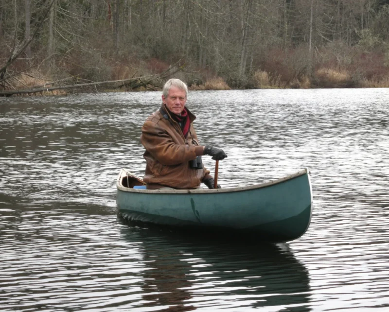 Robert Bateman canoes down a river.
