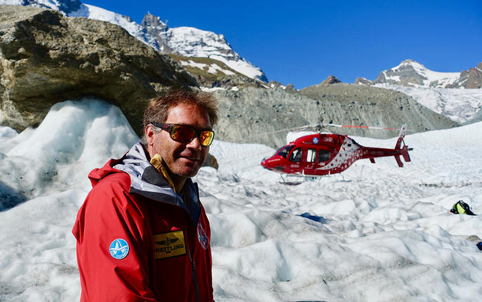 Truffer on a glacier, a helicopter behind him. 