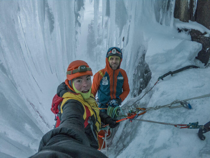 Climbers between the ice wall and a curtain of icicles.