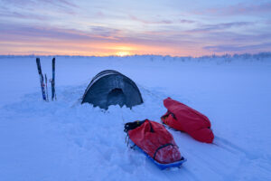 tent, sleds and skis as the sun sets