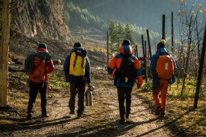 Climbers seen from behind, walking with their climbing gear on a trail.