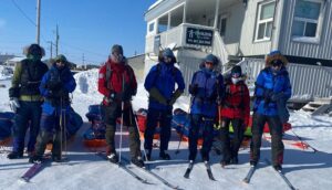 group of arctic skiers standing in front of a building in an arctic village
