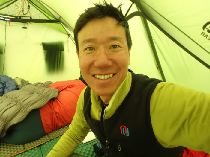 The climber smiles from inside a mess tent. 