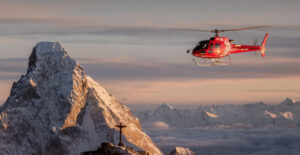 The helicopter flies at dawn at the side of Matterhorn.