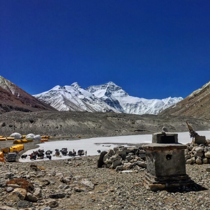 Tents grouped in the mmiddle of an endless plain, with Everest far in background. 
