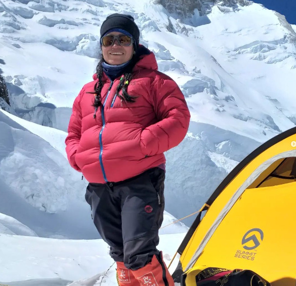Cuenca in front of her tent on Annapurna, with dawn jacket and mountain trousers. 