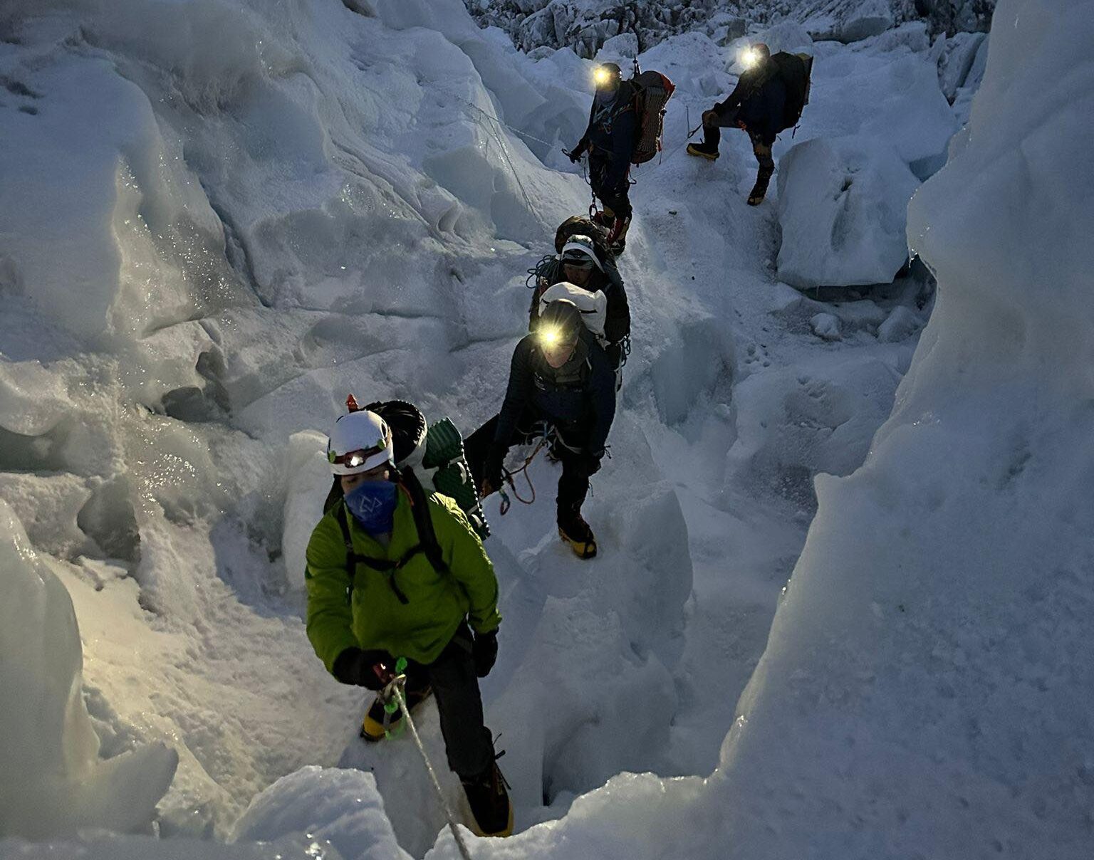 Climbers with headlamps on at dawn, among seracs at Everest Khumbu Icefall