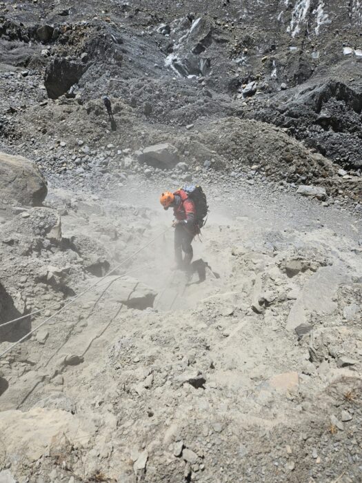 the climber rappels on morrain terrain, rising dust