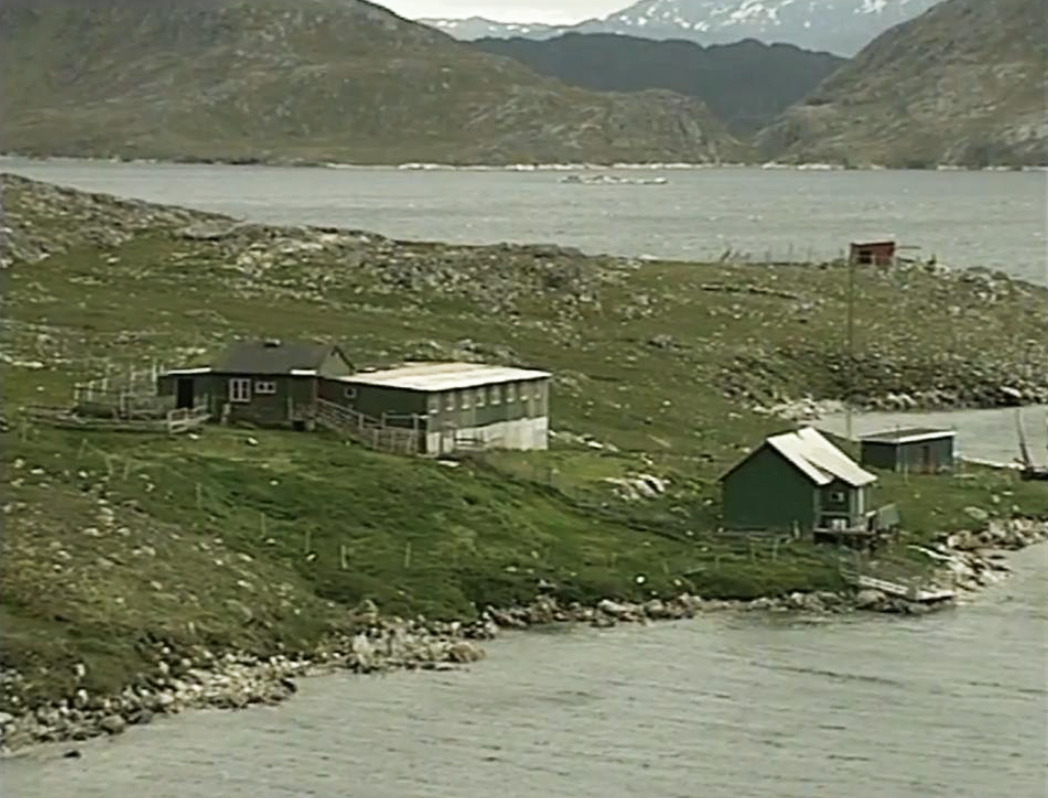 a few tiny cabins on a grassy Greenland coast