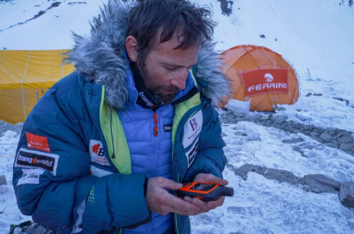 Txikon looks at the InReach device in his hand, in a snowy camp.