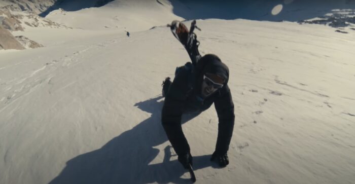 a man climbs up a mountain with skis on his back