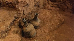 two soiled glass jugs in a mud cellar