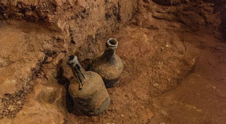 two soiled glass jugs in a mud cellar