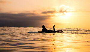 woman on surfboard at sunset