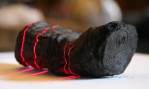 twisted cylinder of coal-like substance with red laser lines