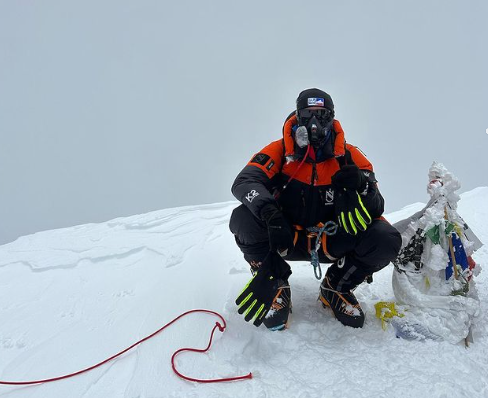 McKenzie can be hardly recognized with cap and O2 mask, on a flattish summit in a foggy day.