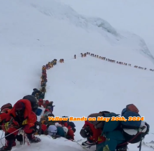 a line of people crosses the lhotse face toward the Yellow Band on Everest in the fog. 