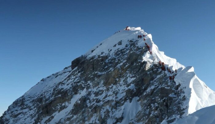A line of climbers follow the edge of the reach toward the summit of Everest Along the Hillary Step