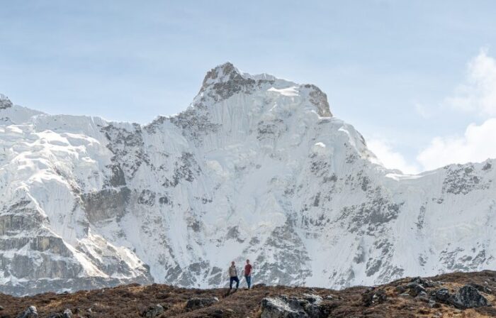 The climbers in front of a vertical mountain face. 