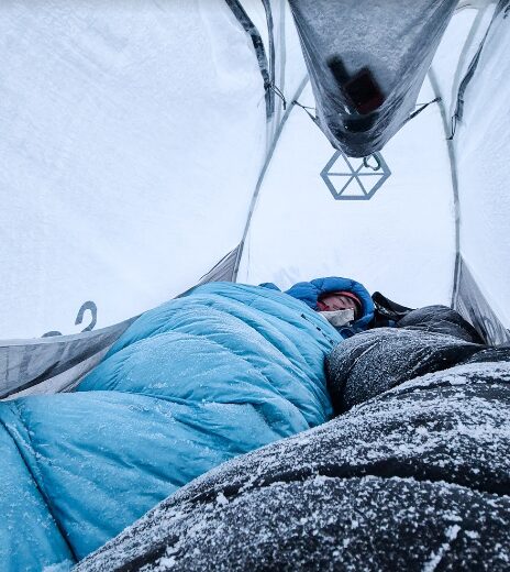 The climbers inside a bivy tent with frosted sleeping bags