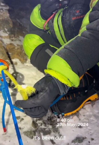 a yellow rope cut and tied to a blue one, held by a climber in high altitude clothes