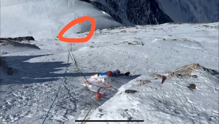 A dead body on a snow slope and ropes going down