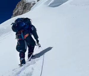 A Sherpa on a snow slope, pulls the rope he is clipped in from inside the packed snow