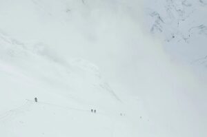 tiny figures of climbers on a huge, while slope on a foggy day on Everest as they climb the Lhotse Face