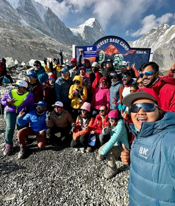 A big team posing in front of the board at Everest Base Camp. 