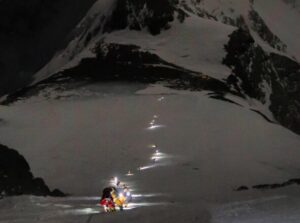A line of Everest climbers in the night, the snow illuminated by their headlamps.
