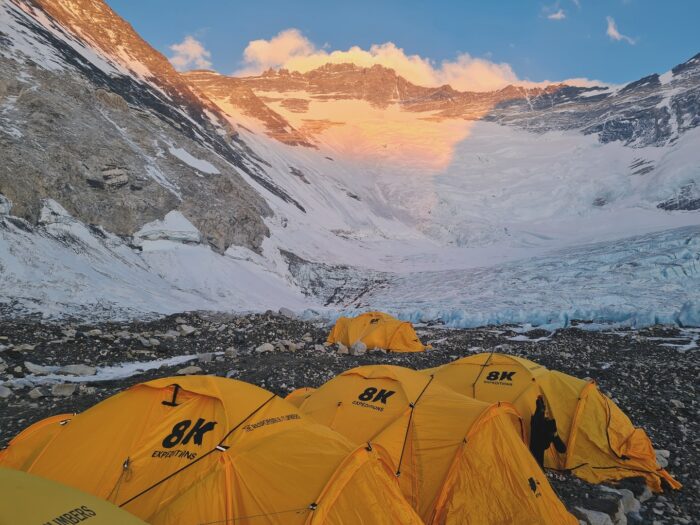 Tents in Camp 2 on rockly, flat ground, and the Lhotse face in background with alpenglow. 