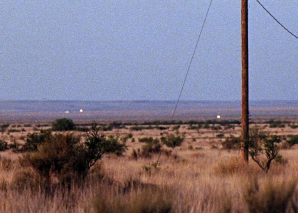 a desert landscape with lights on the horizon