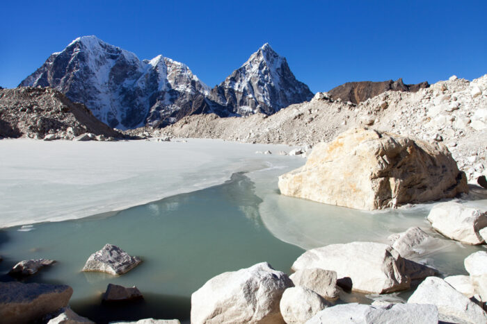 A semi-frozen glacial lake at the Khumbu Valley, Cholatse and Tawoche peaks in background.