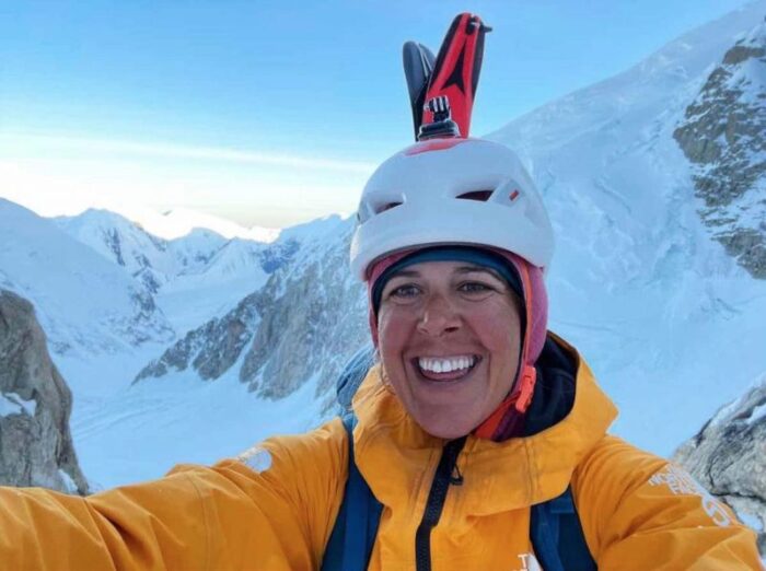 Astorga takes a selfie on a snowy peak, with helmet and skis on her back