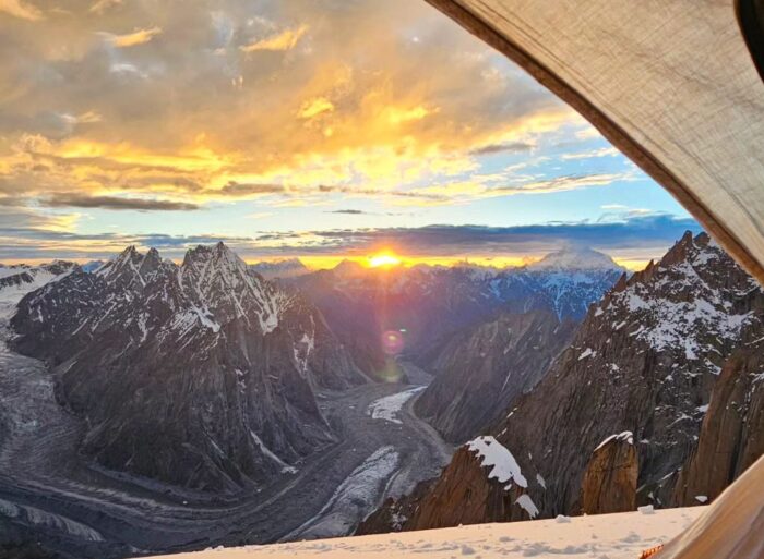 A sea of peaks surrounding a glacier at sunrising, as seen from a tent's door. 