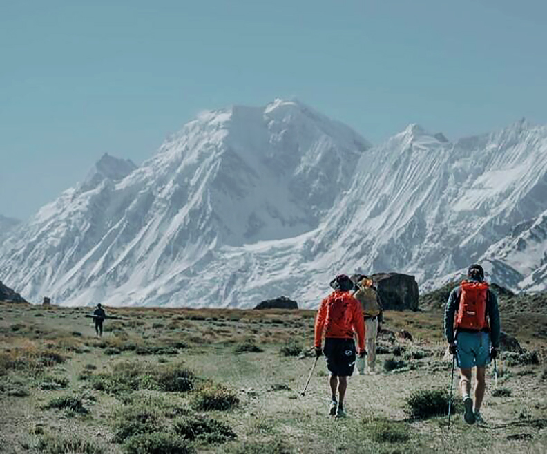 Climbers walk away towards the mountains on a flat, sandy plain