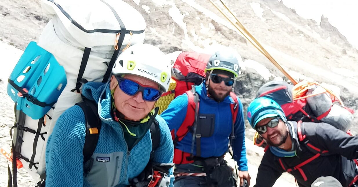 Rghe climber pose for a selfie before departing, with helmets and bagpacks