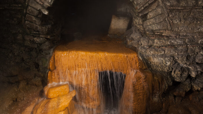 water pours out of a stone arch