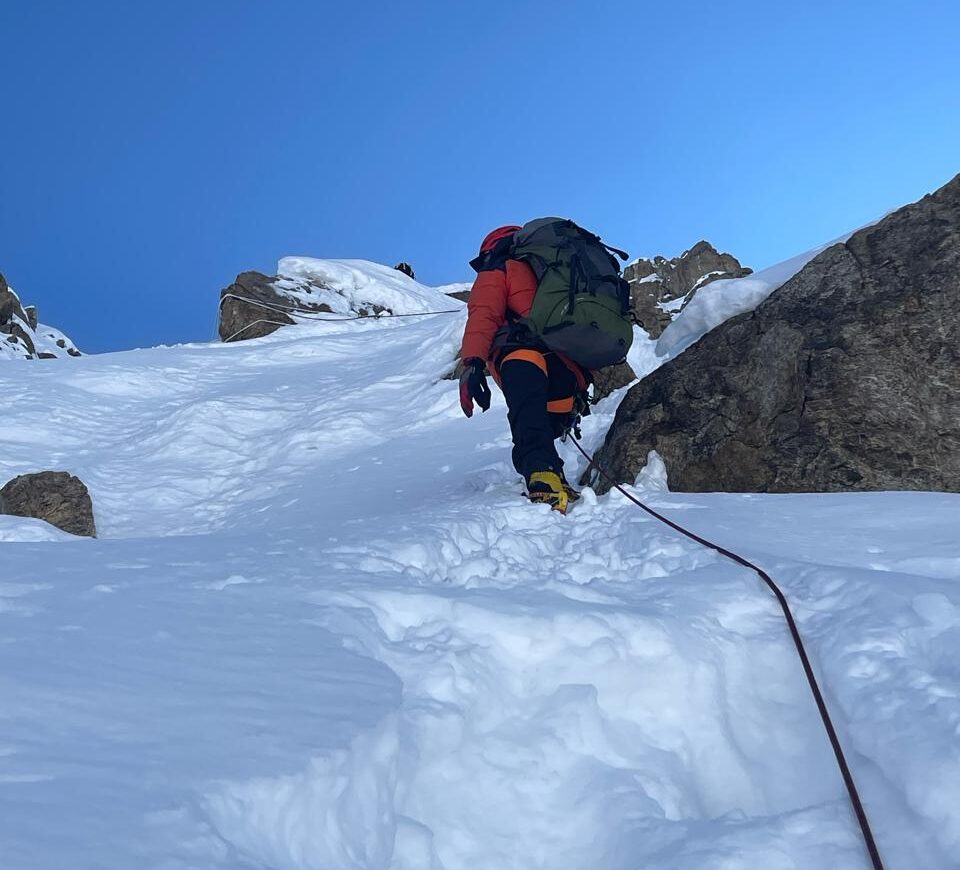 CLimber on a snow-loaded ramp with a rope.