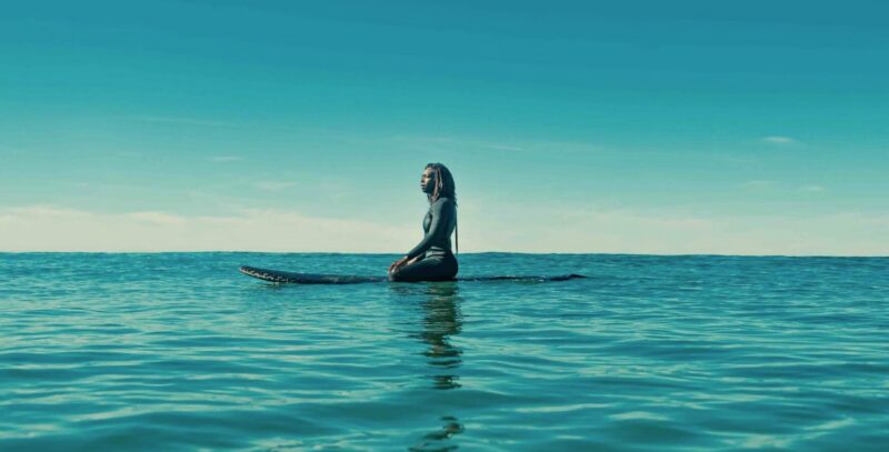 A person sits on a surfboard.