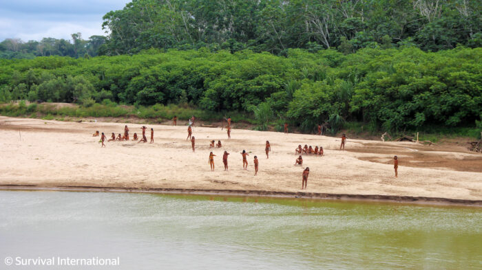 people in loincloths on a sandy river bank