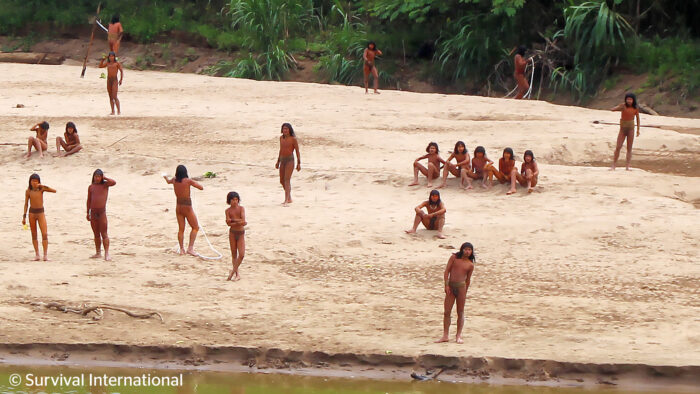 people in loincloths on a sandy river bank