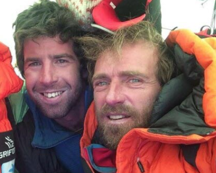 The climbers in a tent, both wearing dawn jackets. 