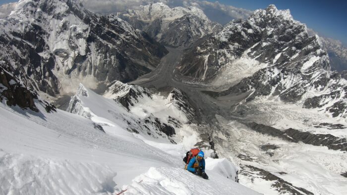 A climber on a steep slope with seracs and crevasses. 