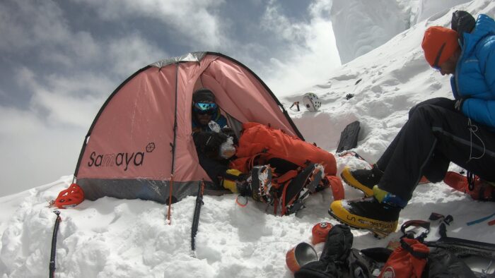 A pink tent on snow among clouds