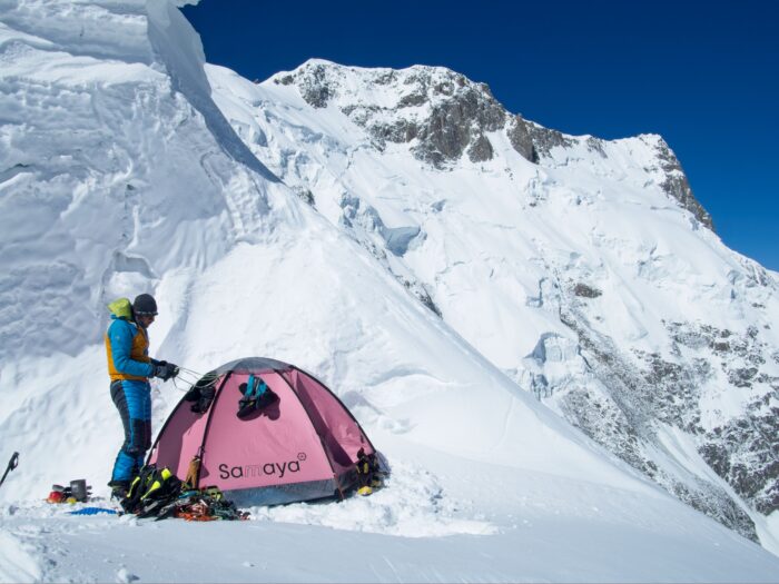 A climber by a small, pink tent high on Muchu Chhish