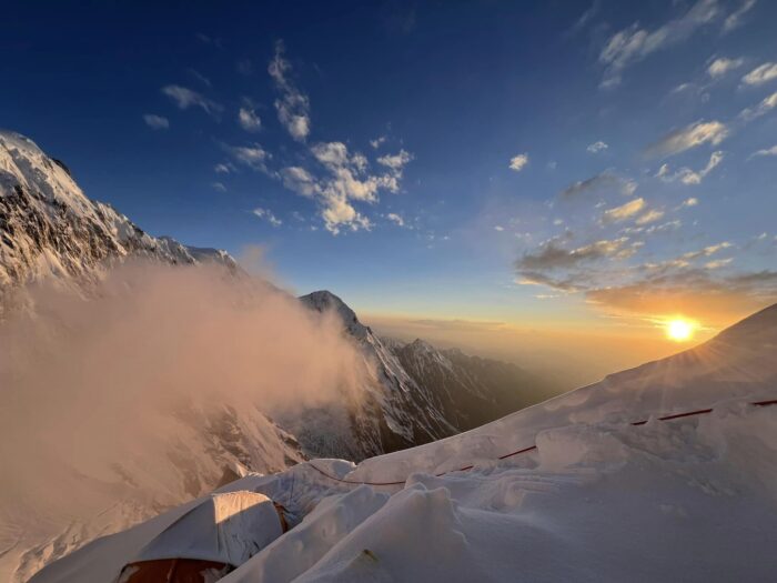 semi buried tents high on a mountain slope at sunset