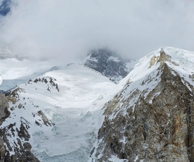 Broad Peak shows a serac barrier and a snow ramp above covered in clouds.